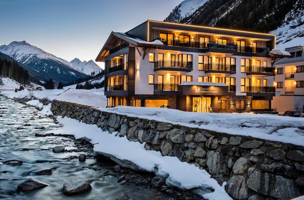 un bâtiment dans la neige à côté d'une rivière dans l'établissement Hotel Modern Mountain, à Ischgl