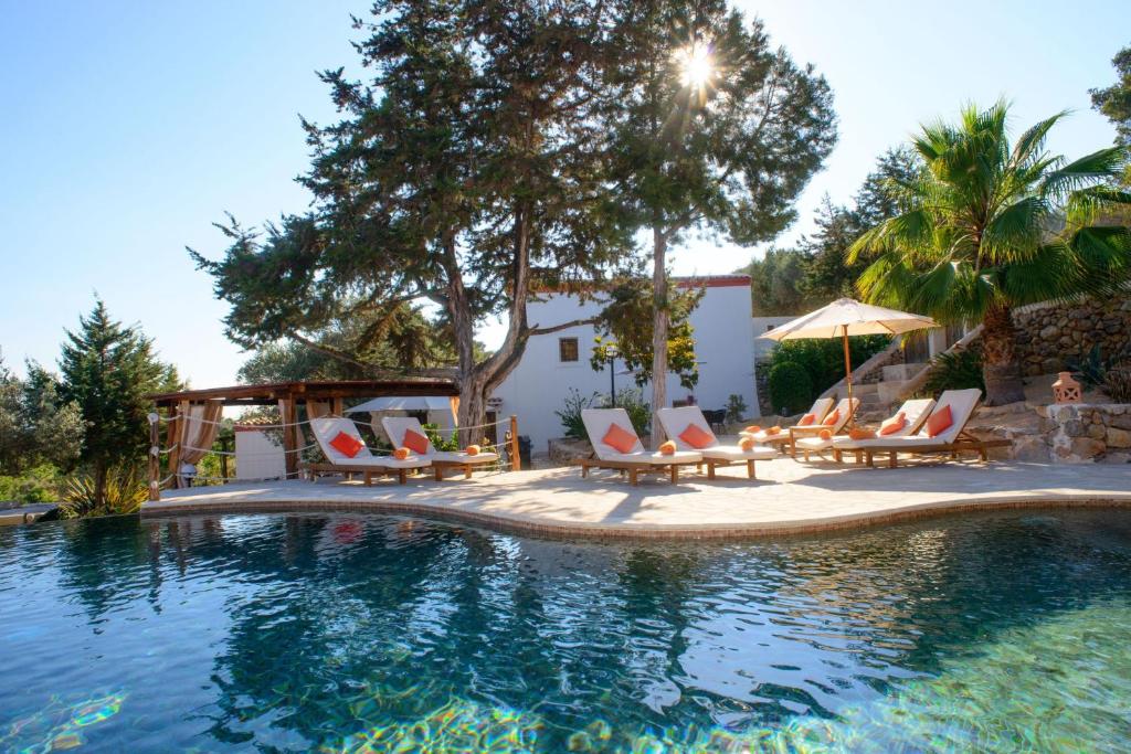 a swimming pool with chairs and an umbrella at Can Vich in Sant Carles de Peralta