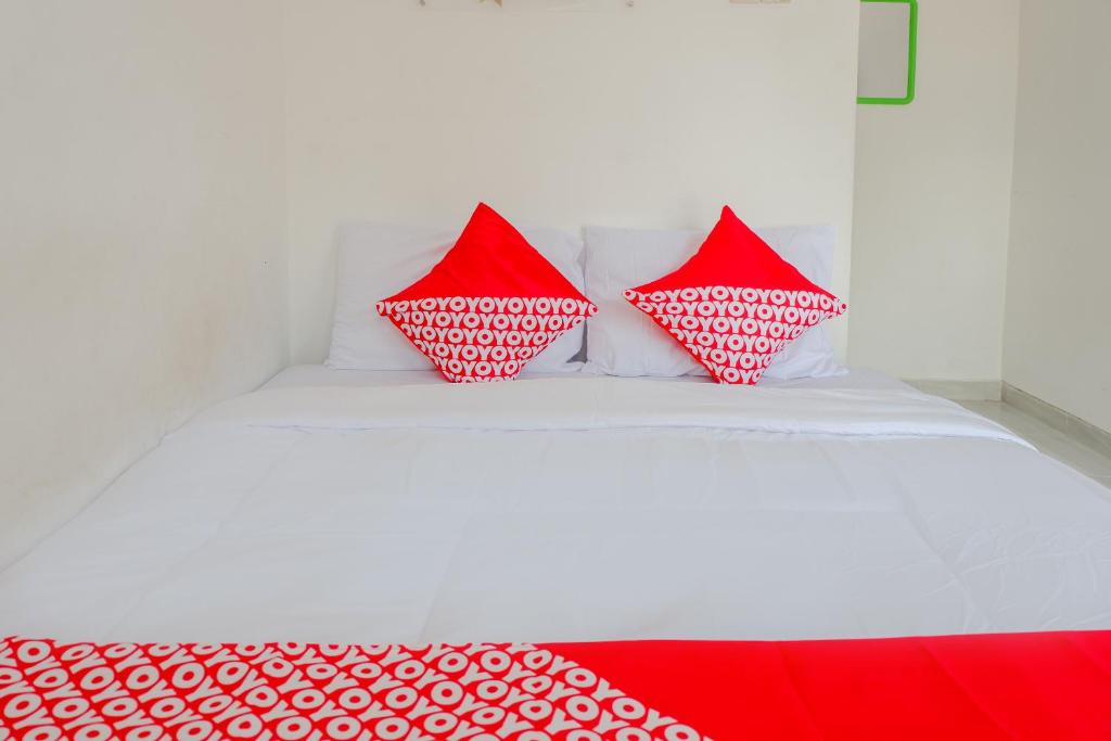 two red pillows sitting on a white bed at Super OYO Capital O 1176 J3 Residence Syariah in Jember