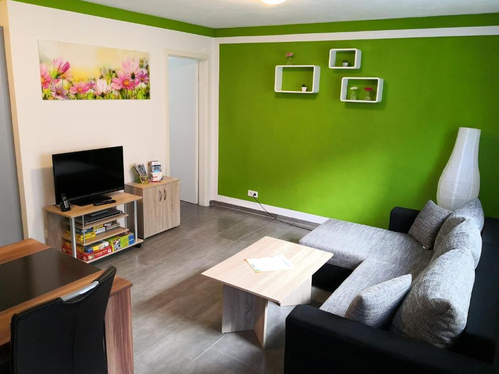 a living room with a couch and a green wall at Ferienwohnung Pfaffenberg in Oberteuringen