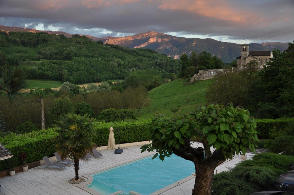 a swimming pool in a garden with mountains in the background at La Bourgeat in Chantesse