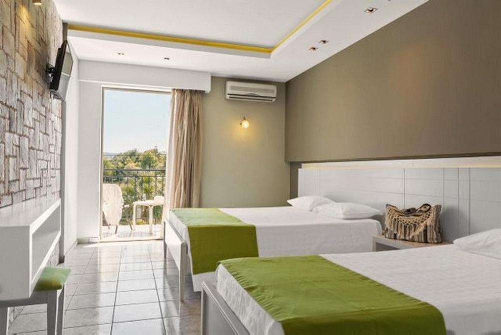 a hotel room with two beds and a balcony at Margarita Hotel - All Inclusive in Laganas