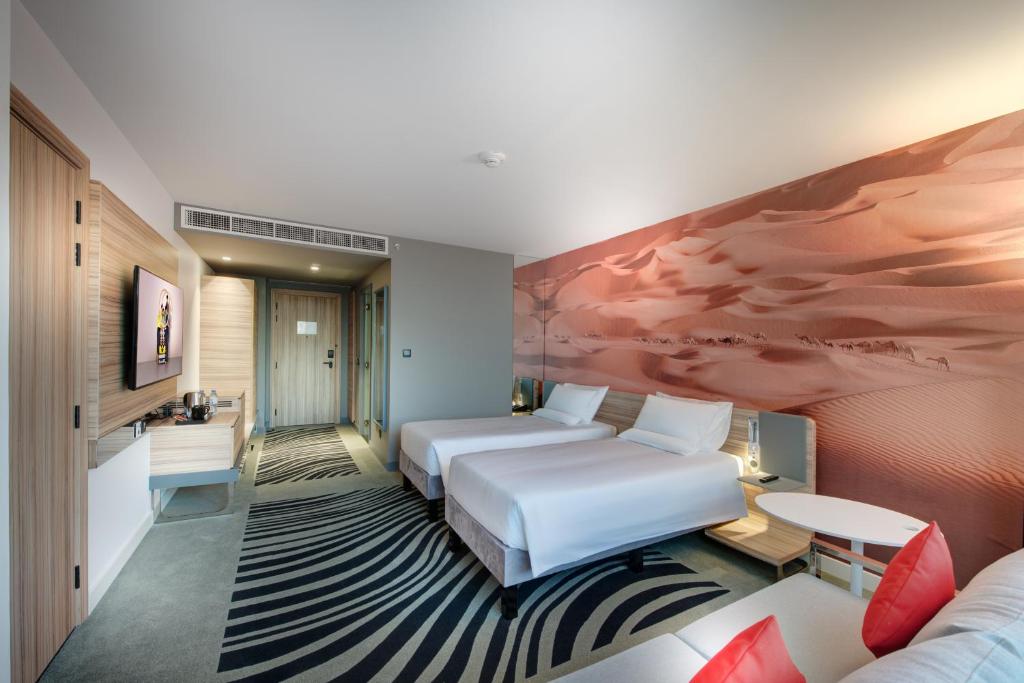 a hotel room with two beds and a couch at Novotel Sharjah Expo Centre in Sharjah
