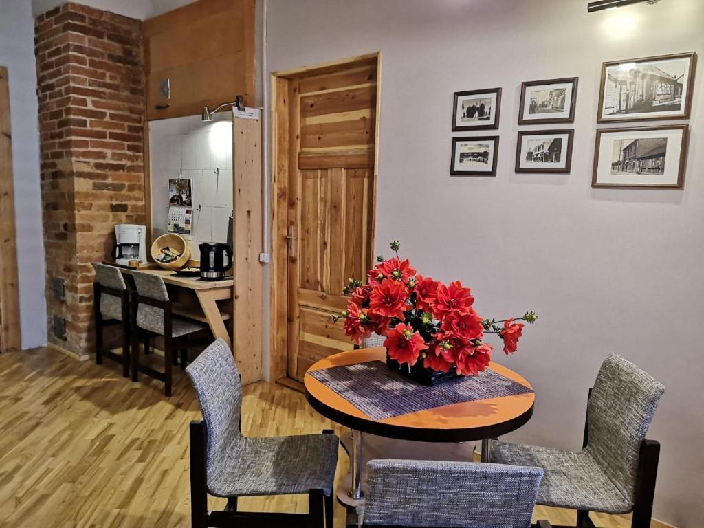 a dining room with a table with a vase of flowers at Centra apartamenti in Jēkabpils