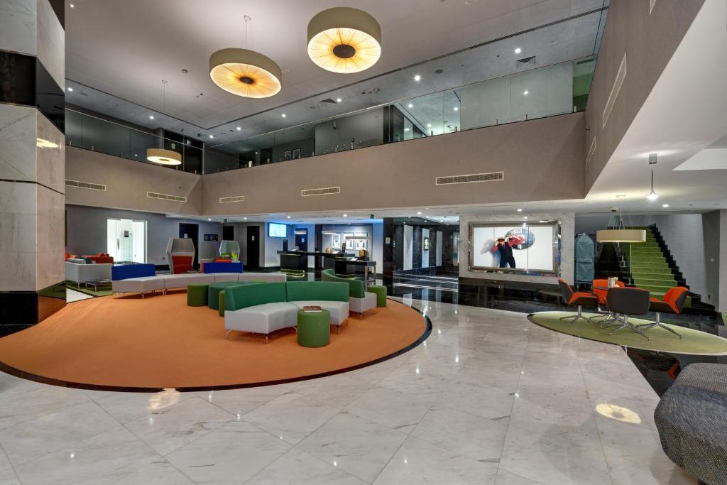 a lobby with couches and chairs and a staircase at Novotel Sharjah Expo Centre in Sharjah