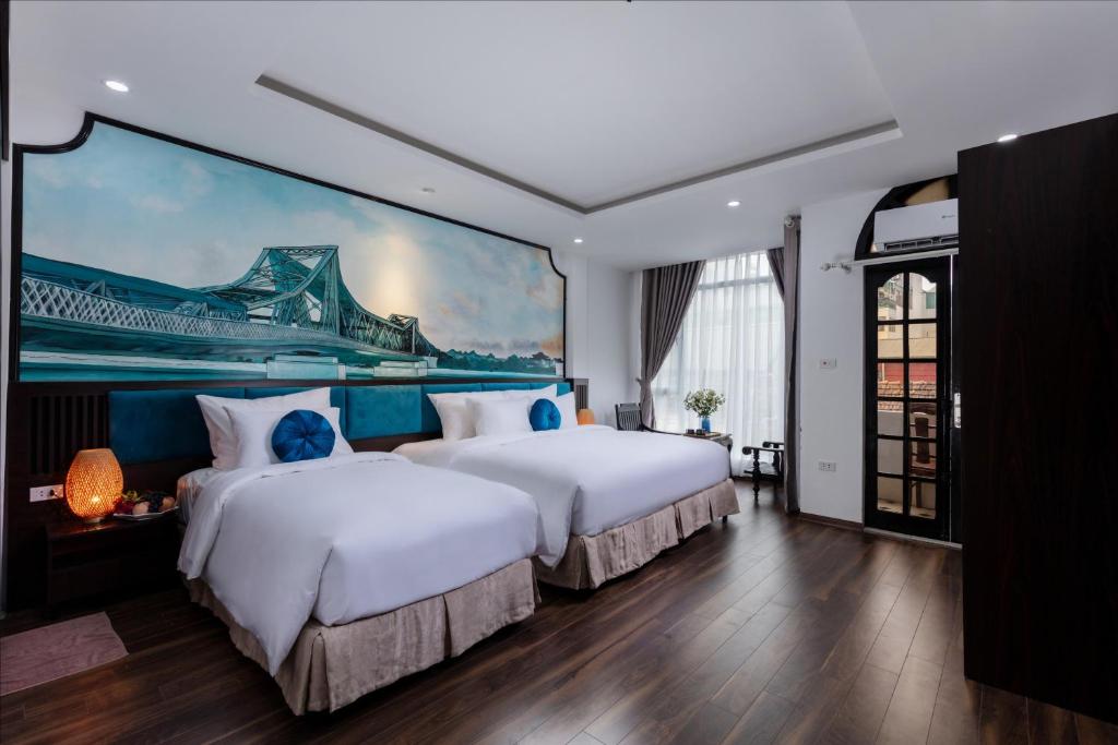 twee bedden in een kamer met een schilderij aan de muur bij Hanoi Center Silk Lullaby Hotel and Travel in Hanoi