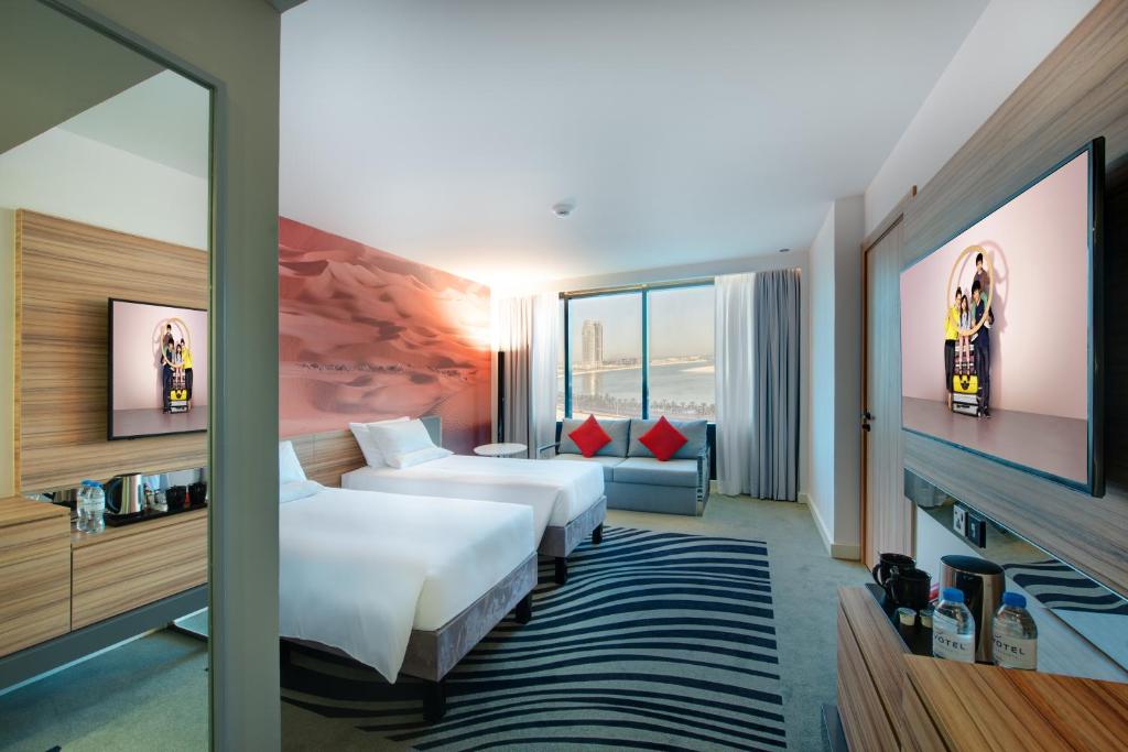 a hotel room with two beds and a tv at Novotel Sharjah Expo Centre in Sharjah