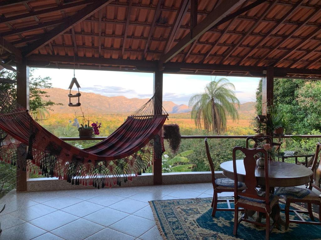 a porch with a hammock and a table and chairs at Pousada Belvedere da Serra in Serra do Cipo