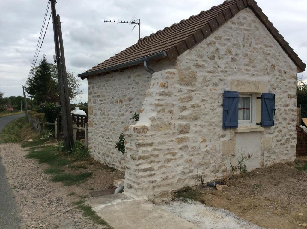 une maison en pierre avec une fenêtre bleue sur le côté dans l'établissement STUDIO 11m2, à Magny-Cours