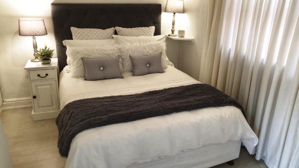 a bedroom with a large bed with two pillows at Carrington Cottage in Cape Town