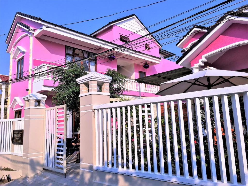 una casa rosa con una valla blanca en Ms Tri Homestay, en Hoi An