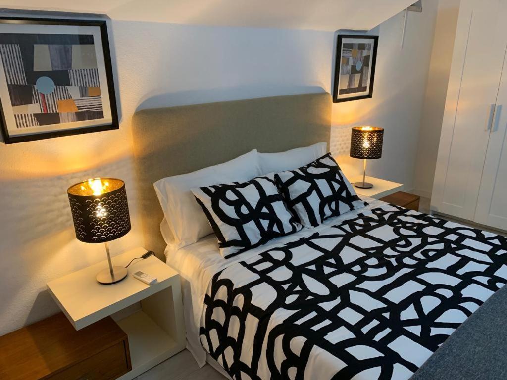 a bedroom with a black and white bed and two lamps at House BLZ in Charneca