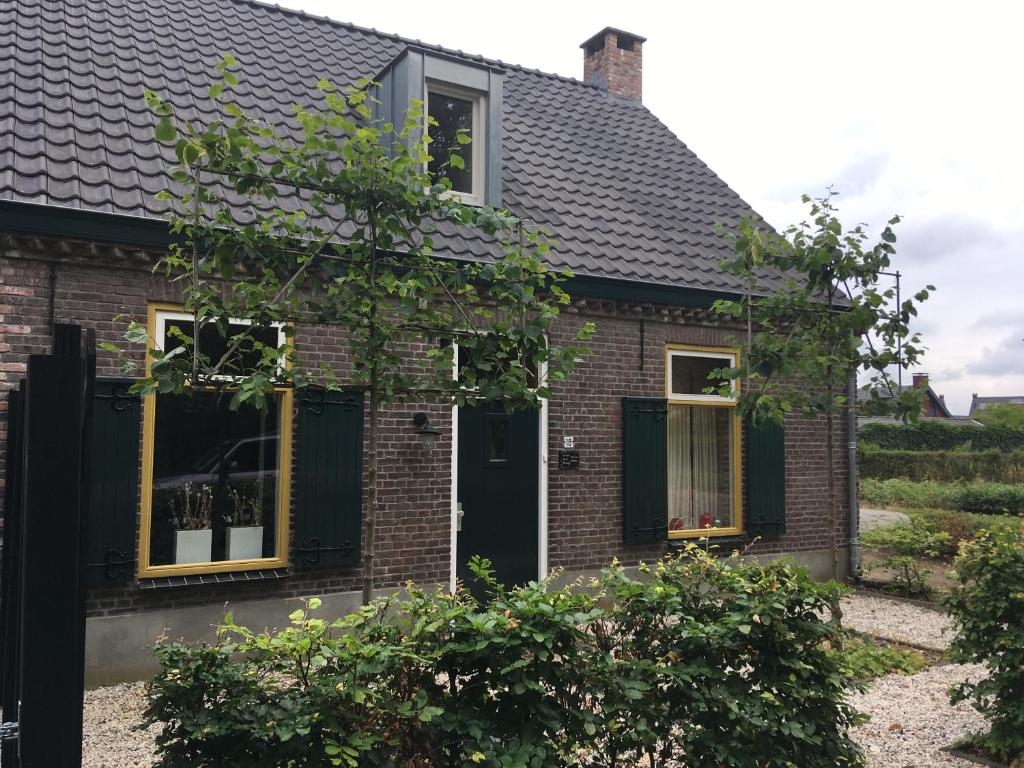a brick house with a black door and windows at Vakantiehuis In het Voorhuis in Dommelen