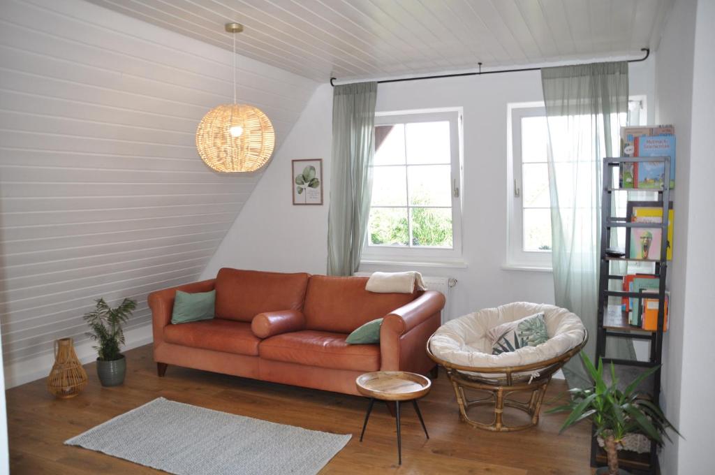 ein Wohnzimmer mit einem braunen Sofa und einem Stuhl in der Unterkunft Schöne, helle FeWo für 4 Personen in Ettenheim