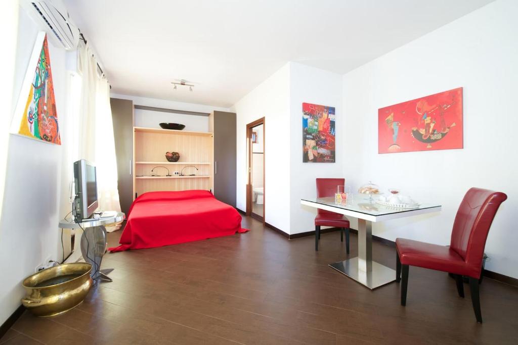 una camera con letto rosso e tavolo con sedie di Casa Turati a Bari