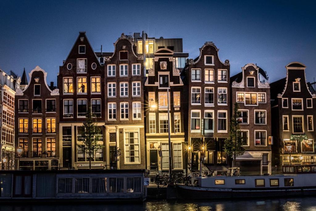 een groep gebouwen naast een kanaal 's nachts bij Hotel Amstelzicht in Amsterdam