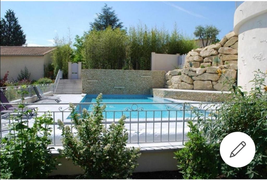 uma piscina num quintal com uma parede de pedra em Les Dentelles de Montmirail em Carpentras