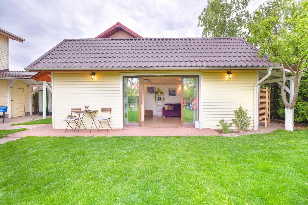 a white house with a table and chairs in a yard at Happy Place - Casuta Galbena in Domneşti