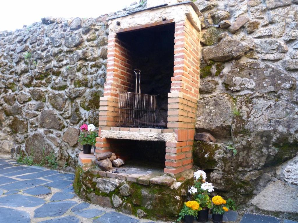 una chimenea de ladrillo en una pared de piedra con flores en Casas del parador - Abadía en Sequeros