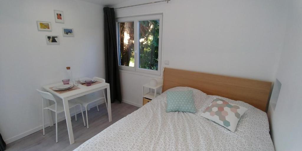 a bedroom with a bed and a table and a window at Charmant studio à Noisiel entre Paris & Disneyland in Noisiel