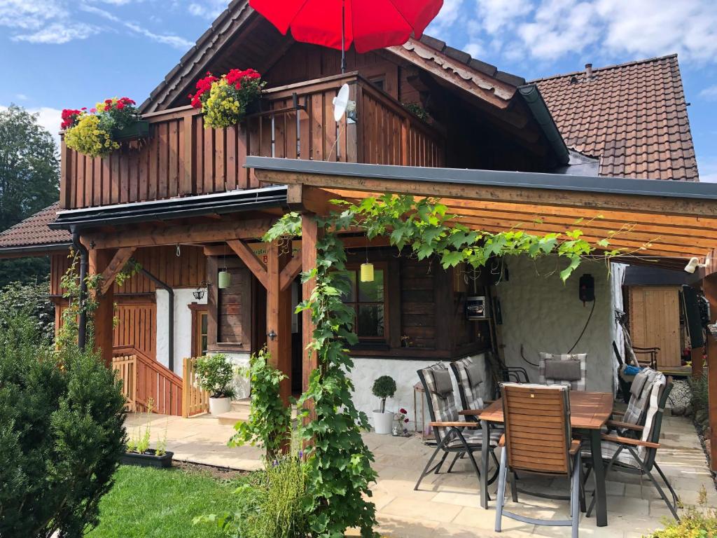 una casa in legno con tavolo e ombrellone rosso di Ferienwohnung Fam. Unterberger a Bad Goisern