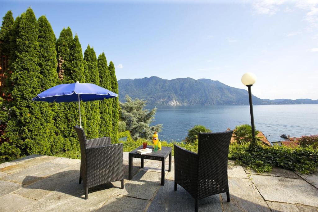 a table and chairs with a blue umbrella and water at Casa Bella Terrazza in Ghiffa