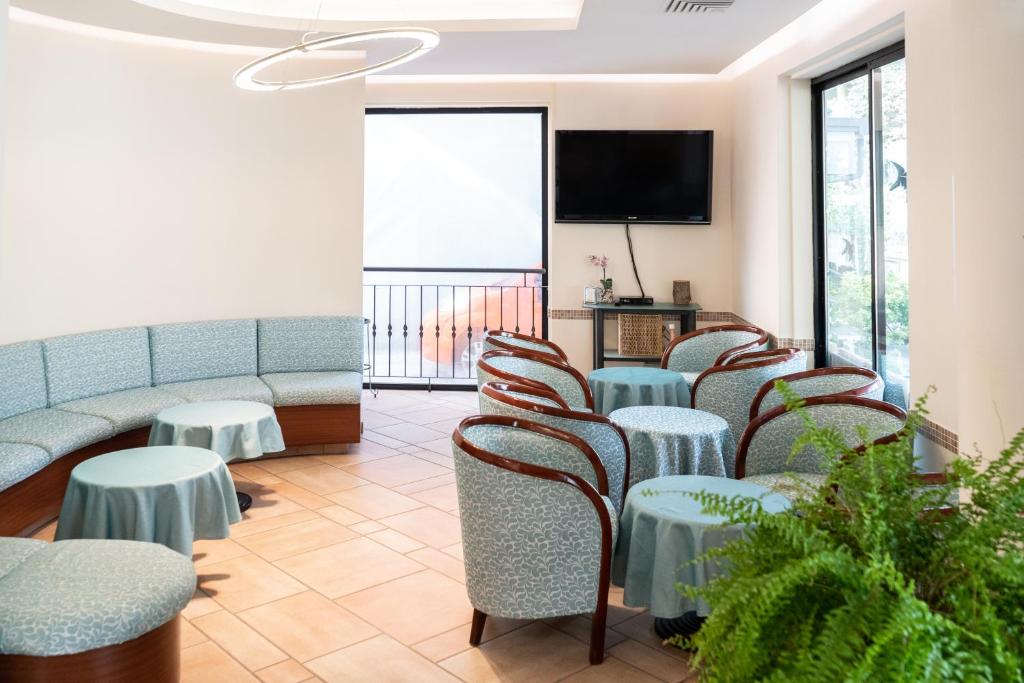 a waiting room with tables and chairs and a flat screen tv at Hotel Tiglio in Rimini