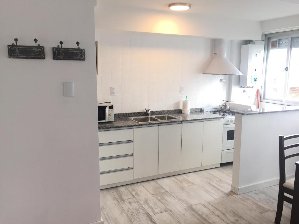 a white kitchen with a sink and a microwave at Departamento Cabo Corrientes con cochera cubierta, sólo alquiler a familias o mayores de veinticinco años in Mar del Plata