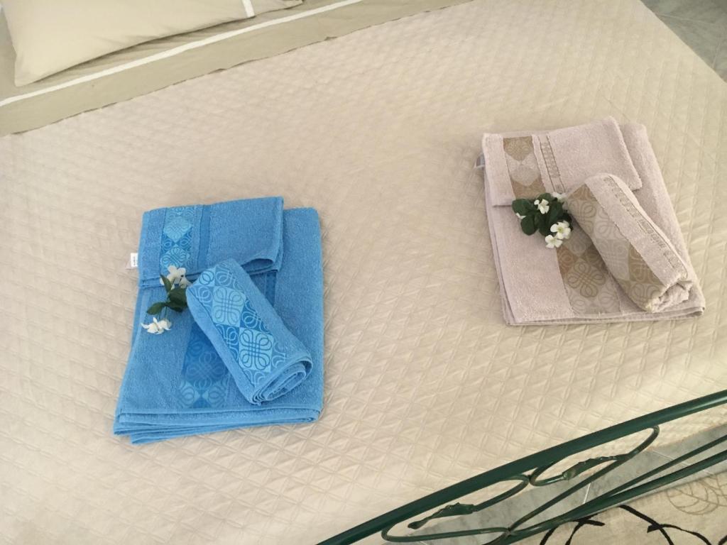Una cama con dos juegos de toallas y flores. en Da Angela, en Orgosolo