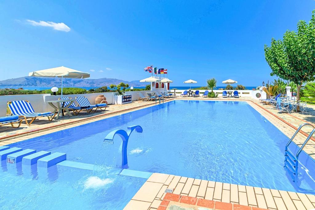 a large swimming pool with chairs and umbrellas at Palladion Hotel in Georgioupolis