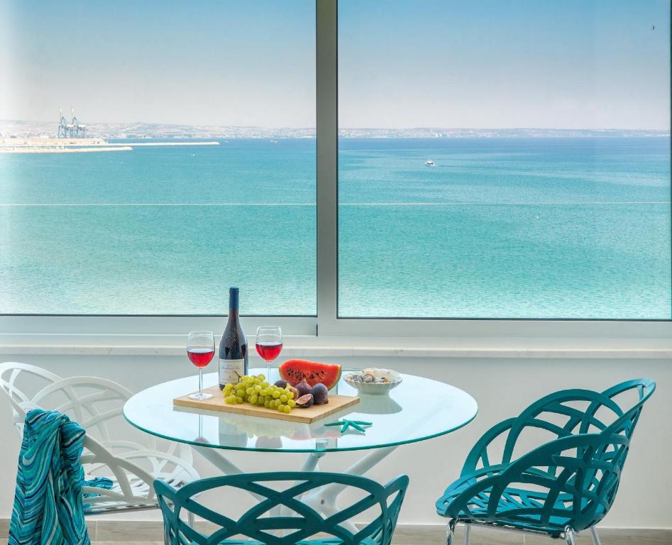 una mesa con dos copas de vino y un plato de fruta en Luxury Penthouse 1BR-Seafront-Seasonal Pool-Central en Lárnaca