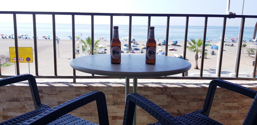 two bottles of beer sitting on a table in front of the beach at PLAYA RINCON DE LA VICTORIA in Rincón de la Victoria