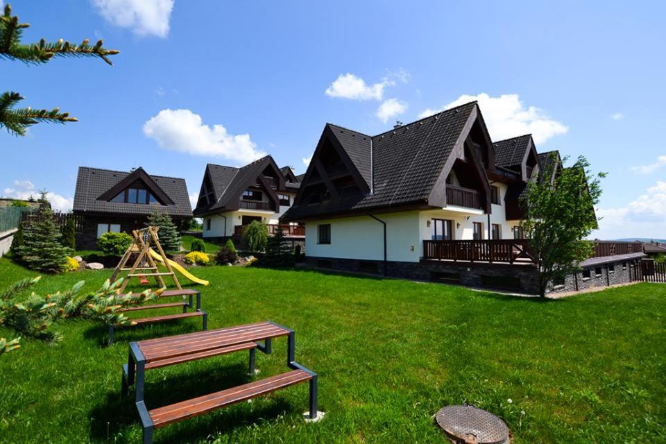una casa con un patio con un banco delante en Apartman Aisha, en Veľká Lomnica