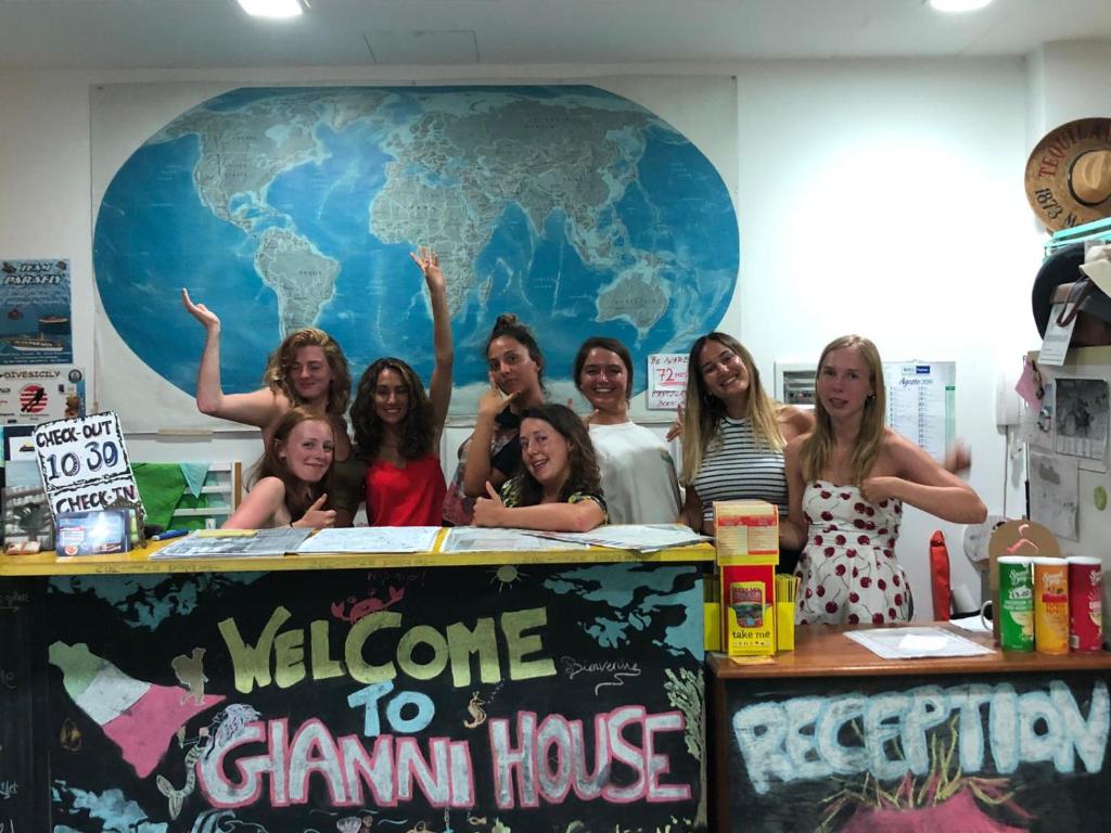 un groupe de personnes debout devant un signe de bienvenue à la maison gamma dans l'établissement Gianni House Backpackers Hostel, à Giardini Naxos