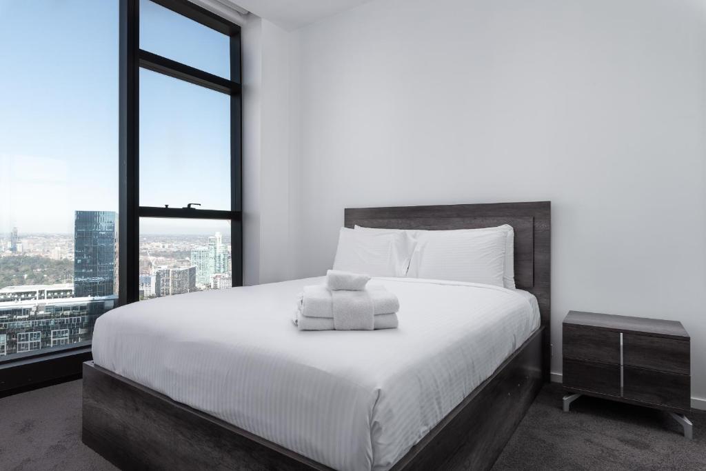 a bedroom with a bed with white sheets and windows at Prima 4511 in Melbourne