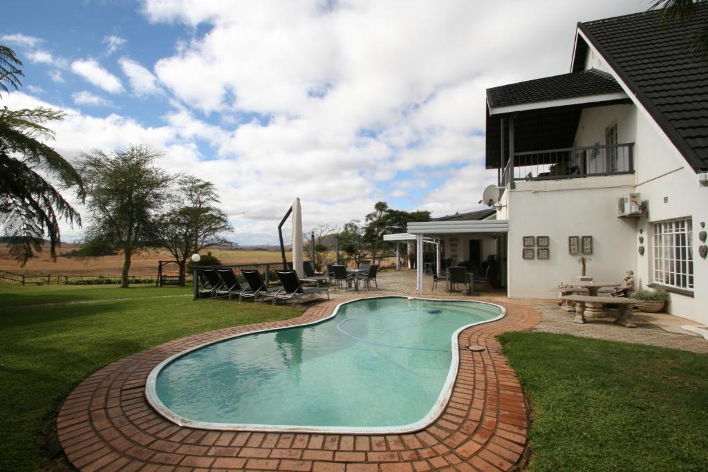 a swimming pool in a yard next to a house at Dusk to Dawn Guesthouse in Piet Retief