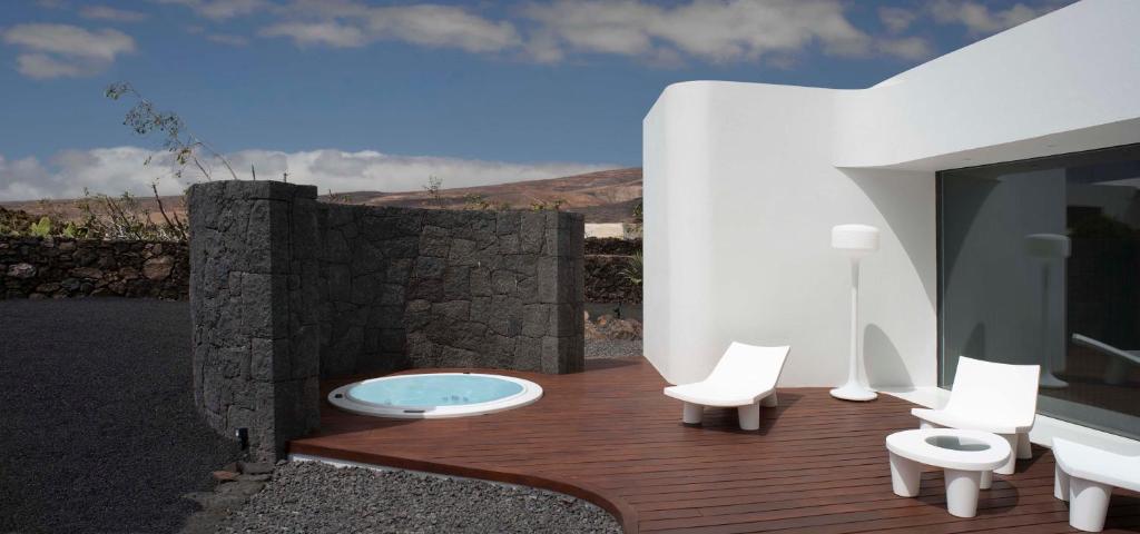 een houten terras met witte stoelen en een hot tub bij VULKANO LOFT in Mala