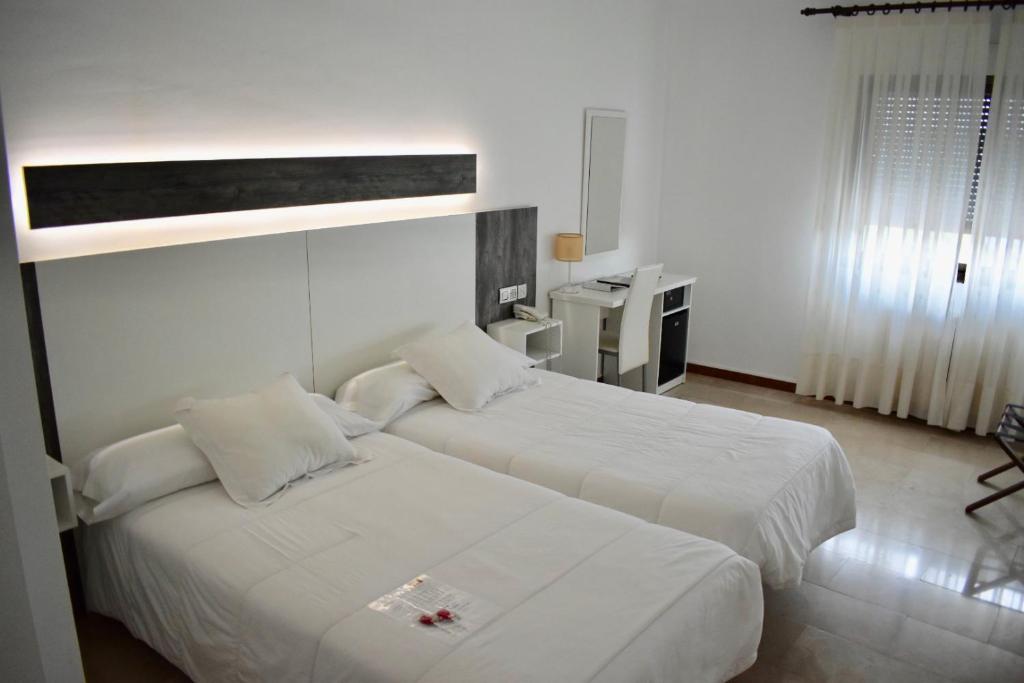 two beds in a hotel room with white sheets at Emperatriz III in Santa Marta de Tormes