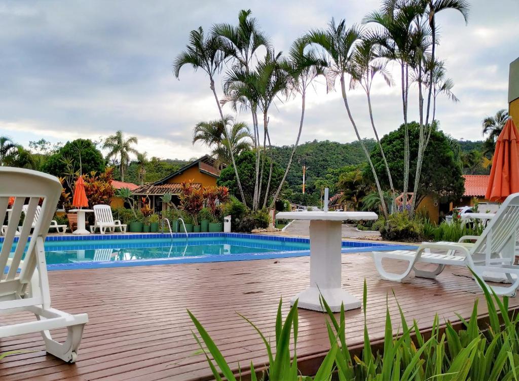eine Terrasse mit Stühlen, einem Tisch und einem Pool in der Unterkunft Chalé Ponta das Canas in Florianópolis