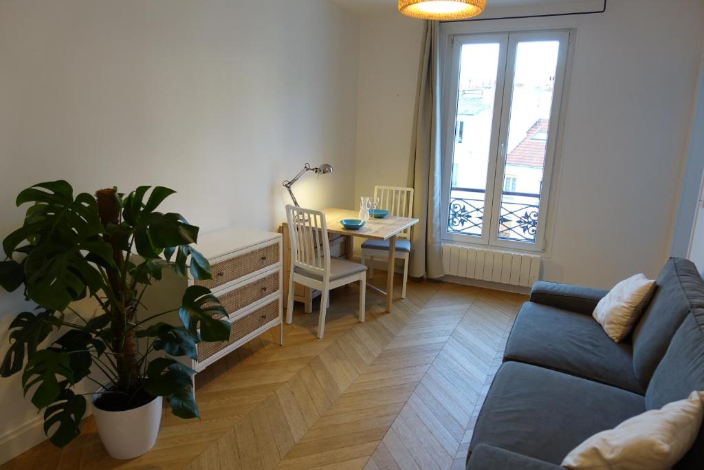 uma sala de estar com um sofá azul e uma mesa em Sunny and quiet apartment em Paris