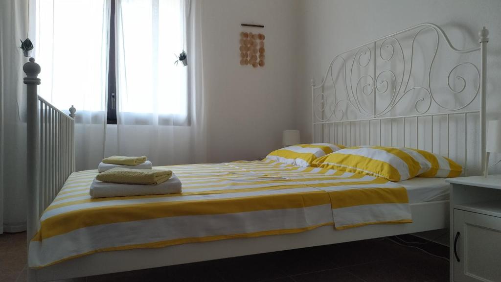 a bed with yellow and white striped sheets and pillows at Apartments Kupine in Bol