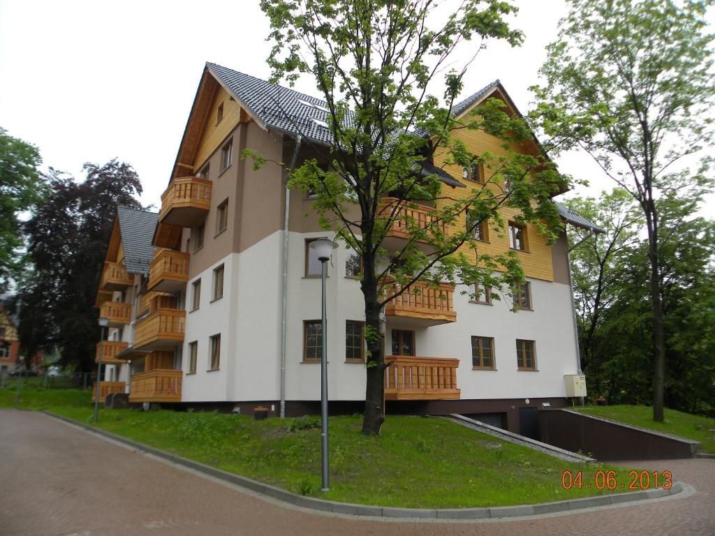 a building with a tree next to a street at Apartament U Anny in Karpacz