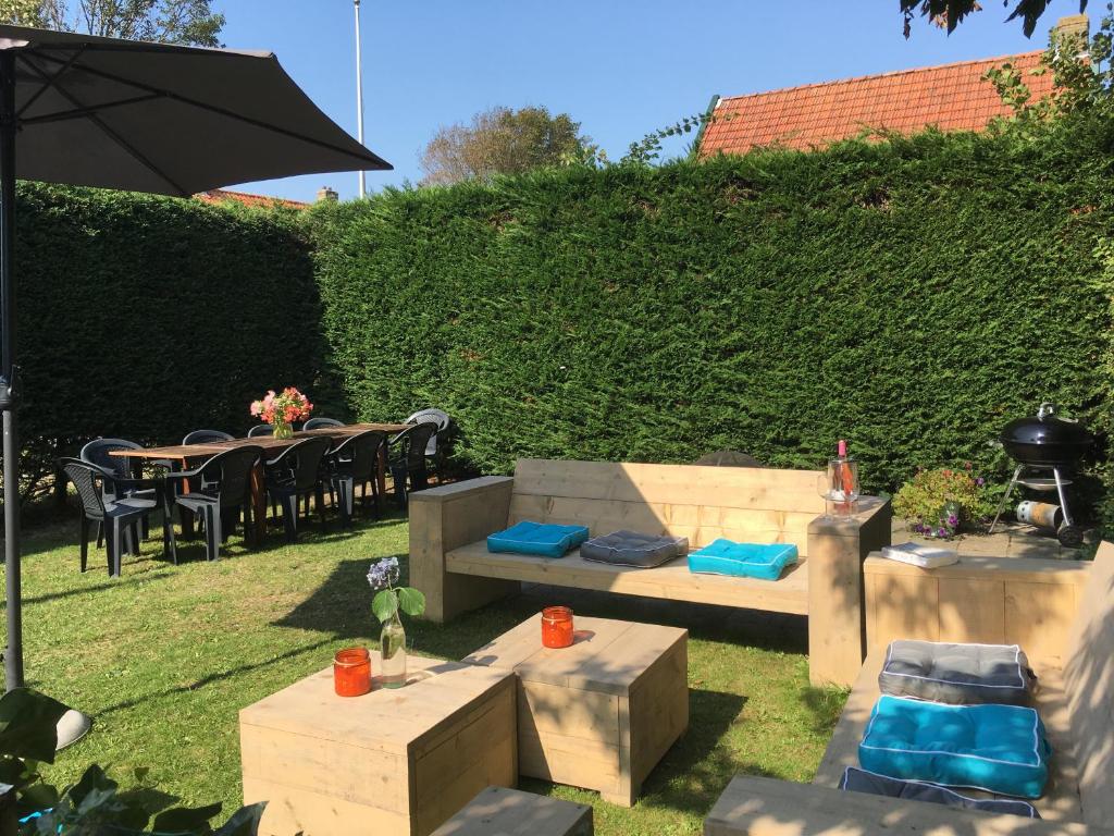 a garden with a bench and tables and an umbrella at Noorderzon in Buren