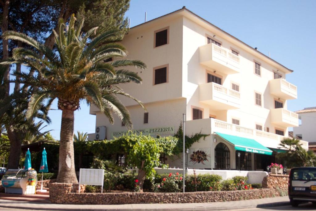 un edificio blanco con palmeras delante en Apartamentos La Cabaña, en Canyamel