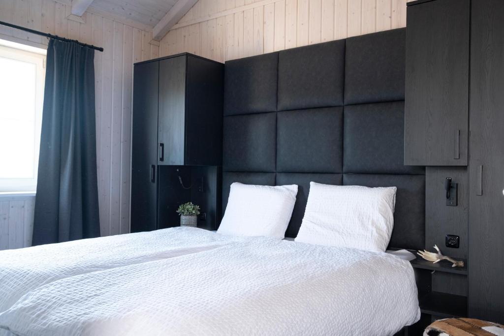 Schlafzimmer mit einem großen weißen Bett mit einem schwarzen Kopfteil in der Unterkunft Kustelberg Lodges in Medebach