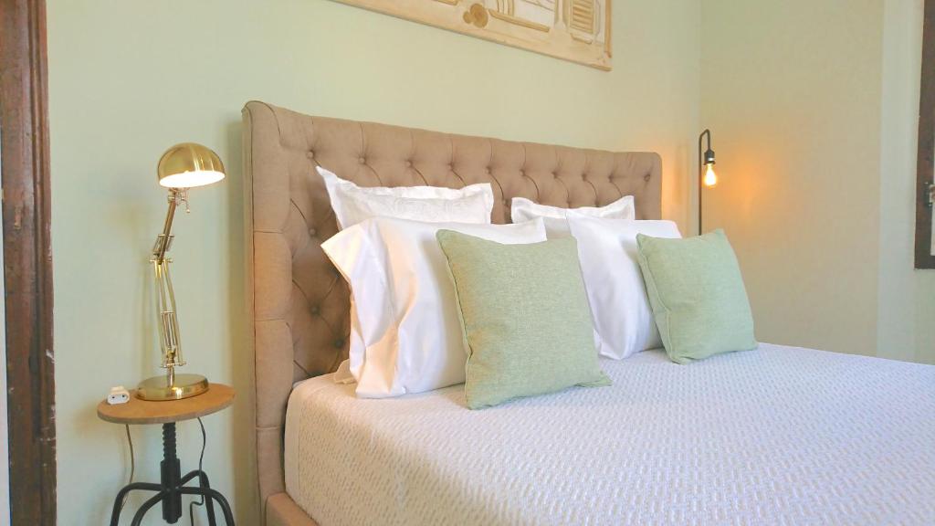 un letto con cuscini bianchi e una lampada su un tavolo di Casa do Alfaiate ® Home&Breakfast ad Almada