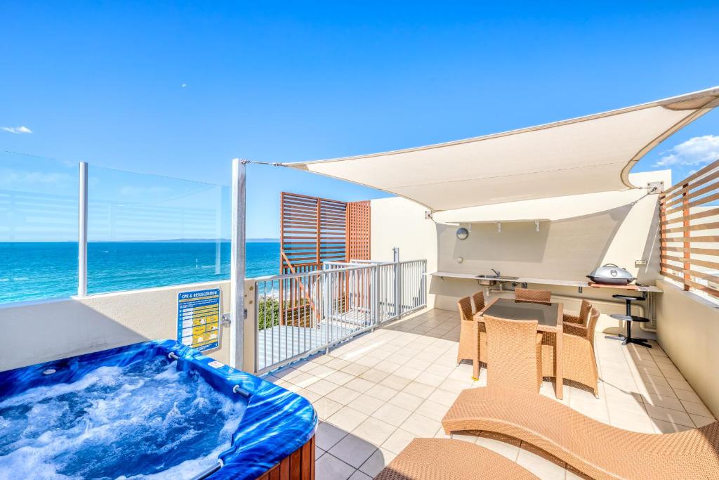 a hot tub on a balcony with a view of the ocean at On The Beach Resort Bribie Island in Woorim