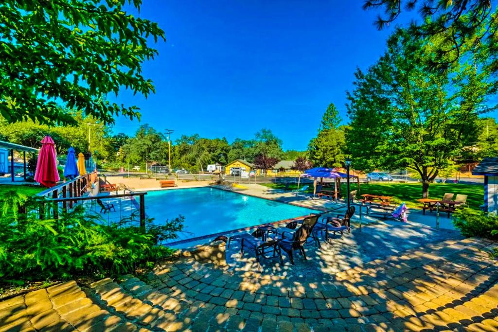 una piscina con sillas y sombrillas en un parque en NEW! Cozy & Secluded House w/Deck - Near Yosemite!, en Tuolumne