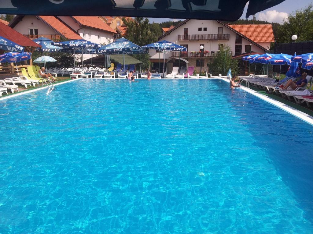 una gran piscina azul con sillas y sombrillas en Vila Romantika en Zlatibor