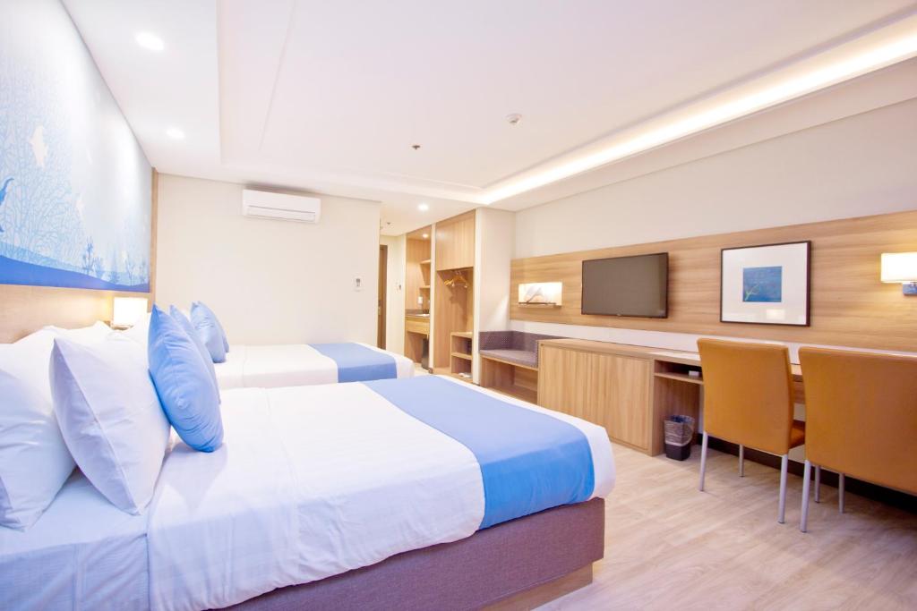 a hotel room with a bed and a flat screen tv at Crown Regency Hotel Makati in Manila